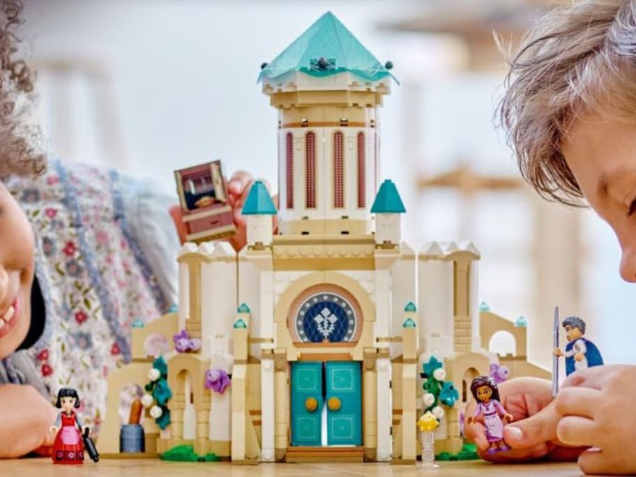 Two kids playing with a LEGO Disney Wish King Magnifico’s Castle