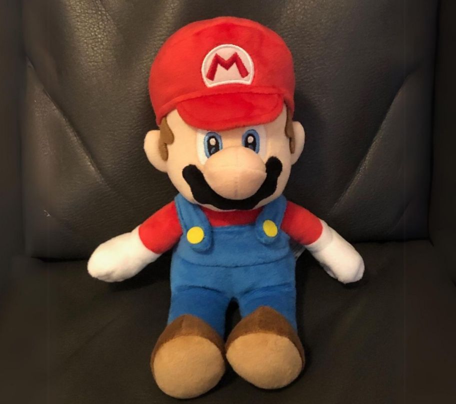 Super mario plush doll sitting on a brown leather sofa