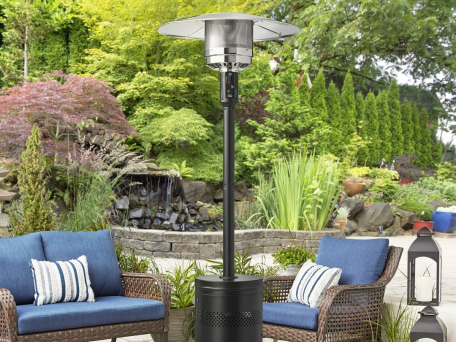 black and silver patio heater in yard with patio furniture in background