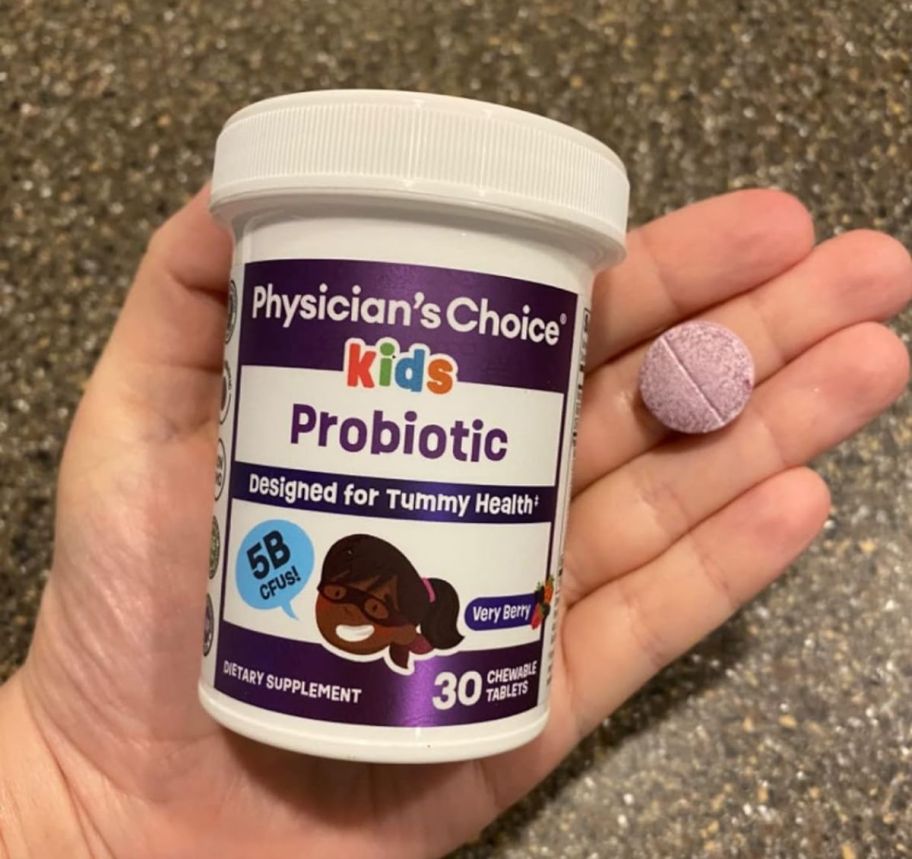 a hand holding a bottle and a chewable Physician's Choice Probiotics for Kids