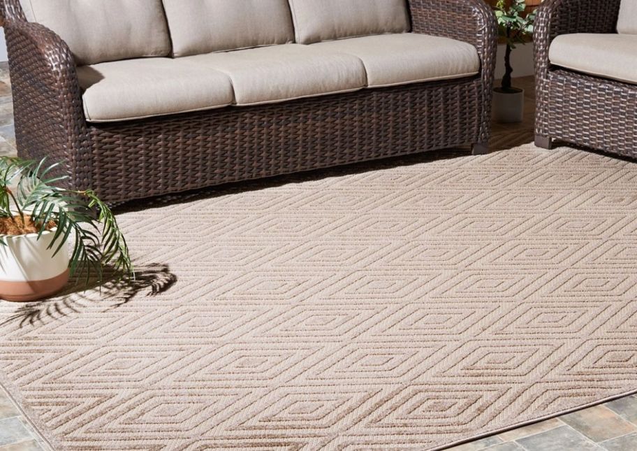 a beige patio rug shown with an outdoor sofa