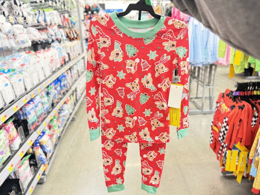 hand holding up set of rudolph christmas print pajamas on hanger