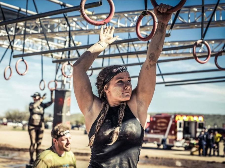 A girl onlinepeting in a Spartan Race doing a a ring course