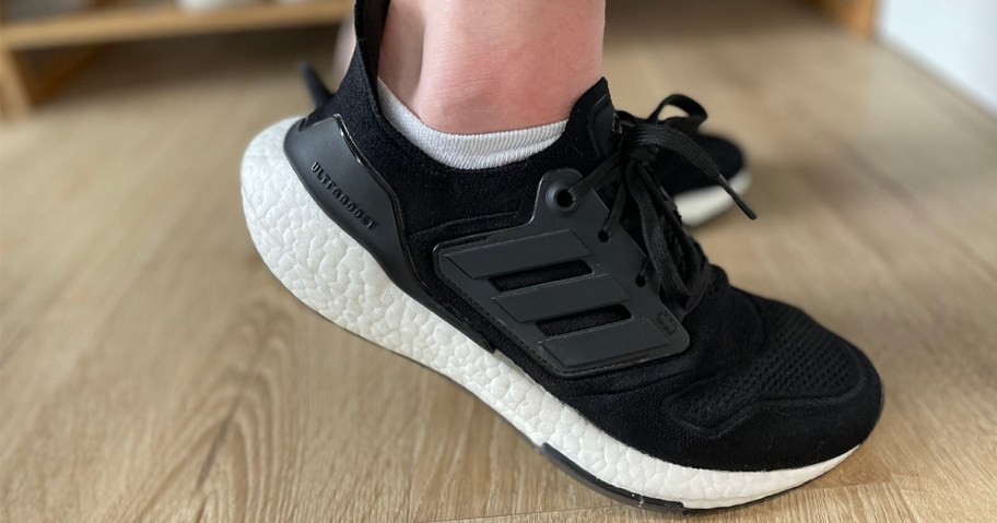 person wearing black and white adidas ultraboost shoes 