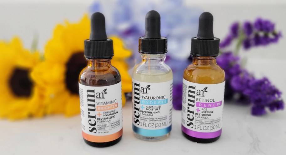 art naturals anti-aging serum trio displayed with flowers behind them