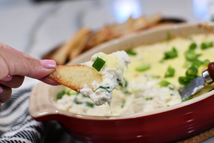 dipping a wonton into crab rangoon dip