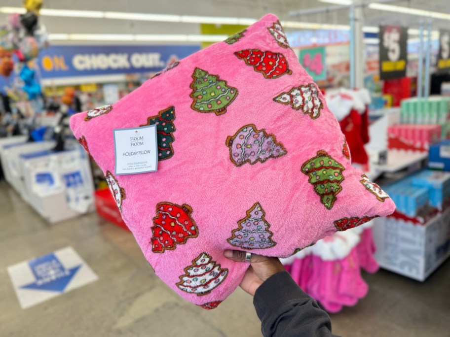 hand holding pink throw pillow with christmas trees