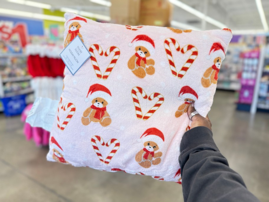 hand holding white throw pillow with teddies and candy canes