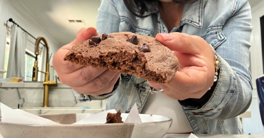 holding a half of chocolate protein cookie