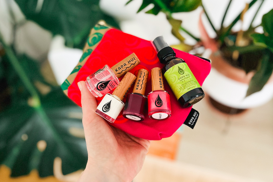 hand holding a hot pink cosmetic bag with kapa nui nail polish on top