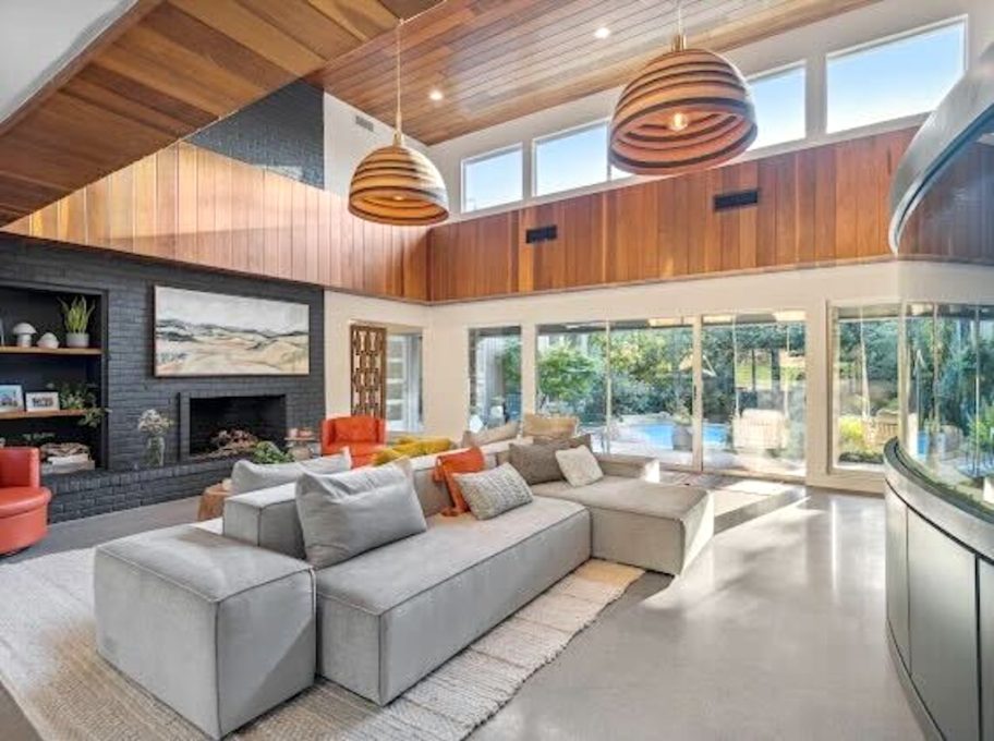 open two story living room with wood panel walls and large windows and gray sectional sofa