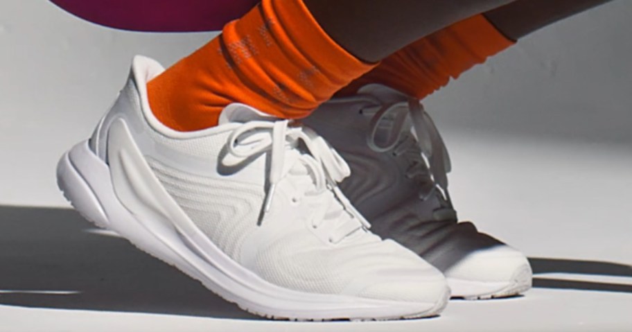 women's ankles and feet wearing orange socks and white running shoes