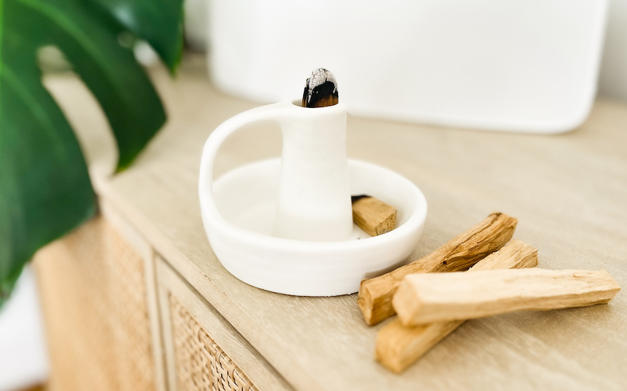 close up of palo santo in white holder with sticks on table