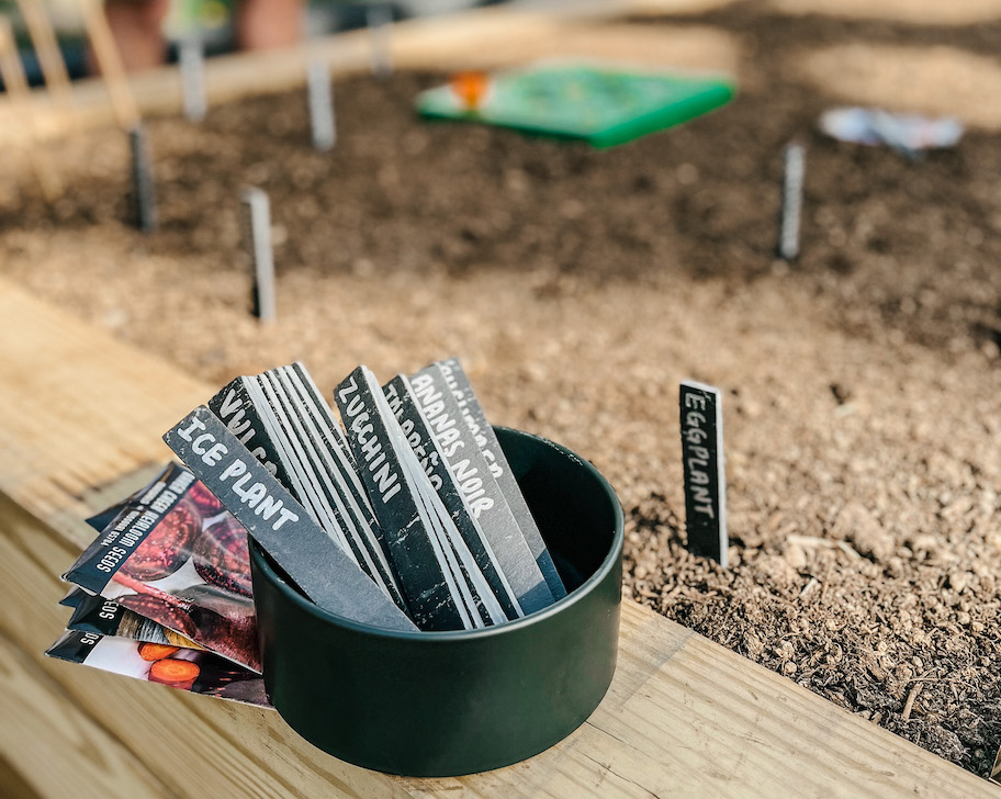 round black bowl with garden markers inside sitting on raised garden bed