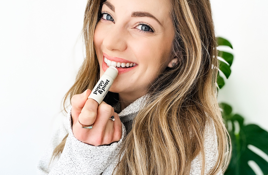 close up of woman putting on poppy and pout chapstick