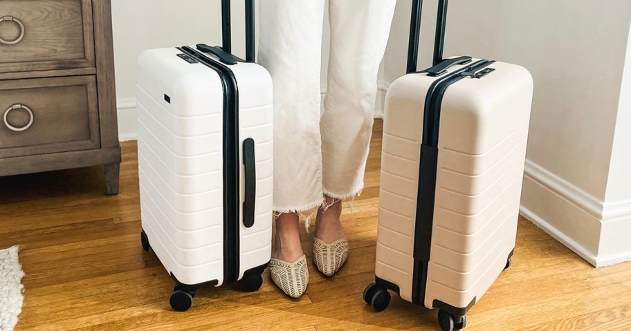 woman standing with white and tan luggage 