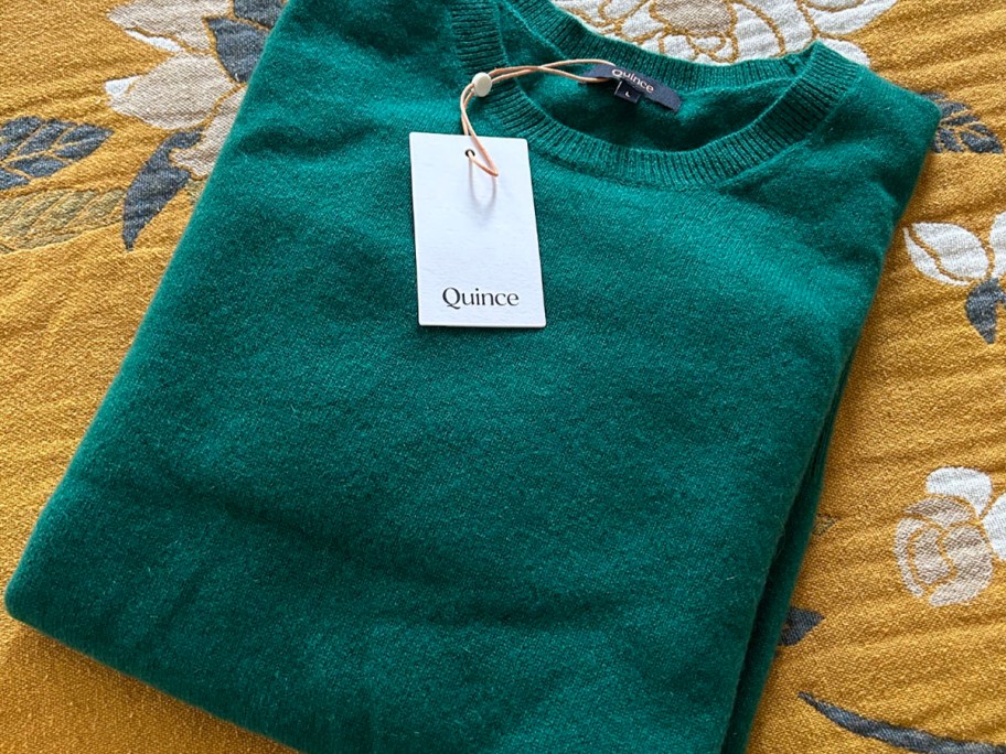 green cashmere sweater laying on floral onlineforter