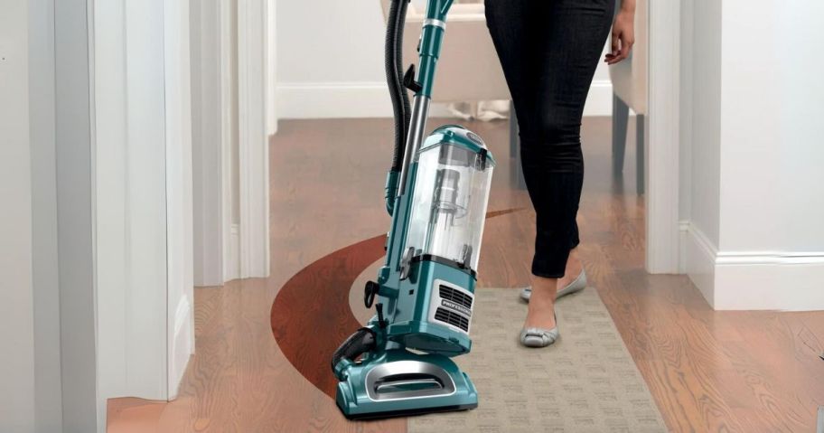 a woman vacuuming a hardwood floor with a shark navigator