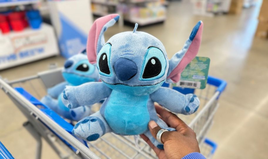 a womans hand holding a stitch plush