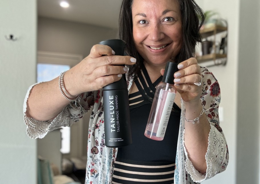 woman holding spray tan mister and bottle