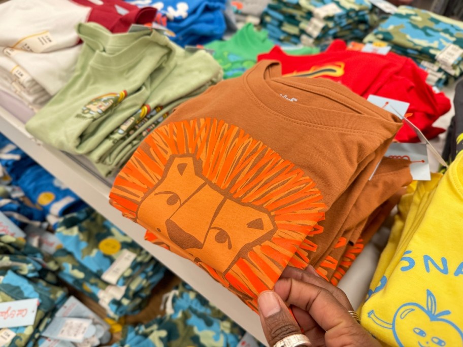 hand reaching for a kid's orange shirt with a bear on it