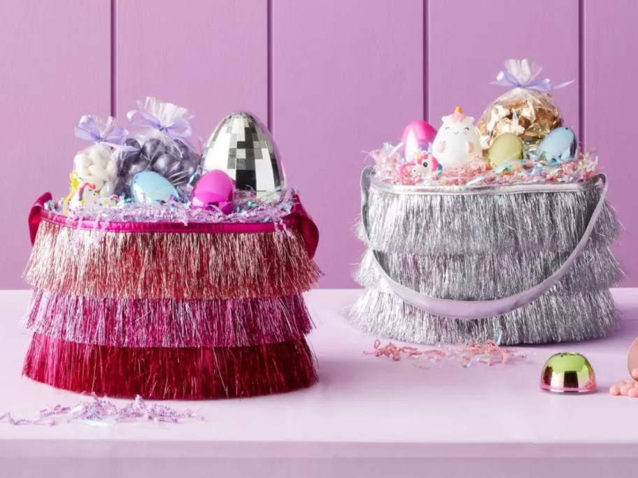 a pink and a silver fringe Easter basket with candy and eggs in them