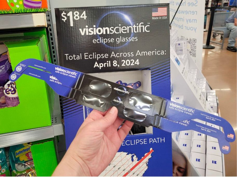 womans hand holding 2 pair of eclipse viewing glasses 