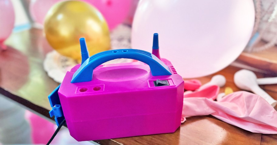 pink and blue balloon pump on table near balloons