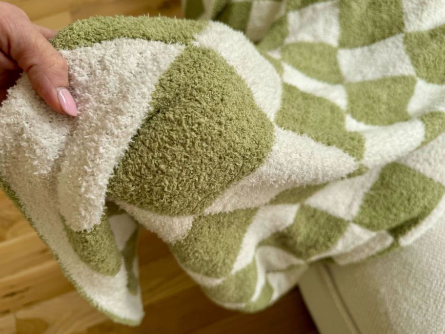 A woman holding a Checkered Throw Blanket in Green