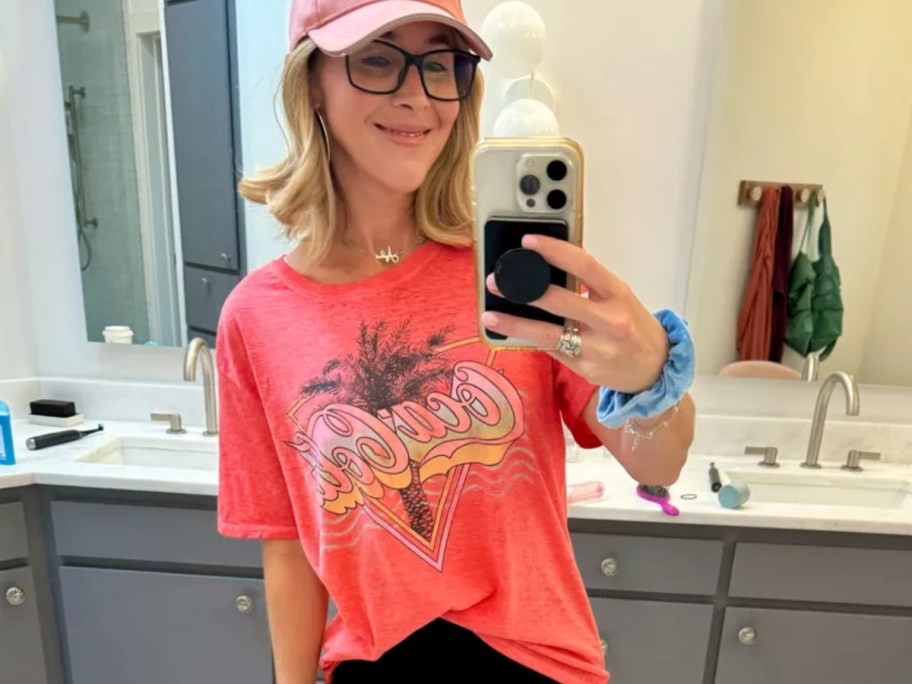 Collin taking a selfie wearing a coral color Coca Cola vintage style tshirt and pink baseballcap