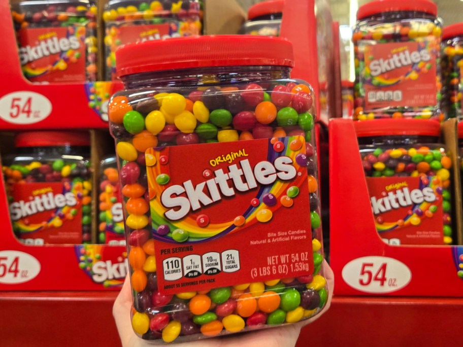 Hand holding Skittles Original Chewy Candy 54oz Bulk Jar at Sams club