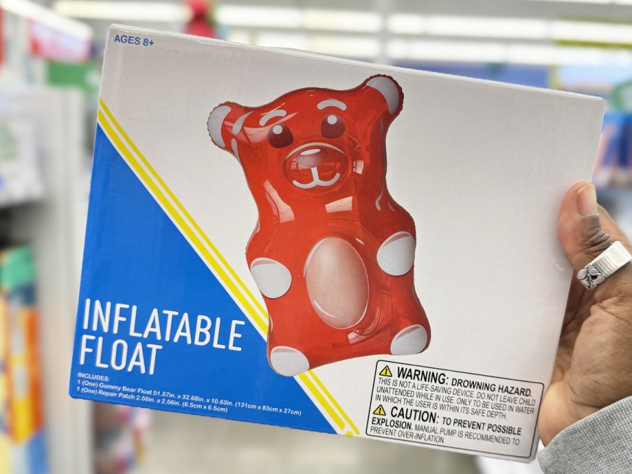 hand holding up a red gummy bear shaped pool float