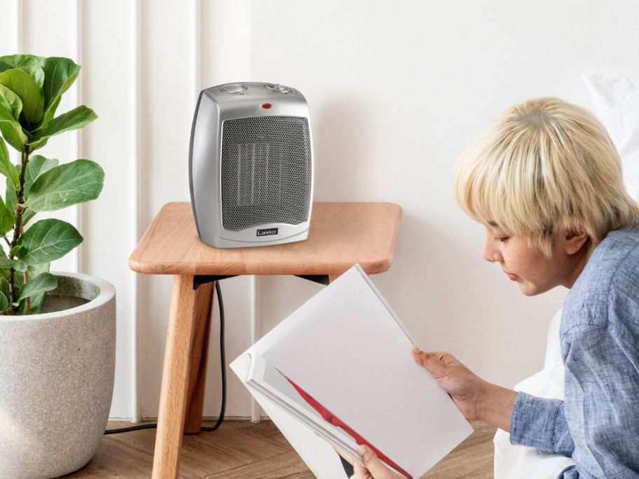 person reading beside Lasko Electric Ceramic Space Heater sitting on tv tray