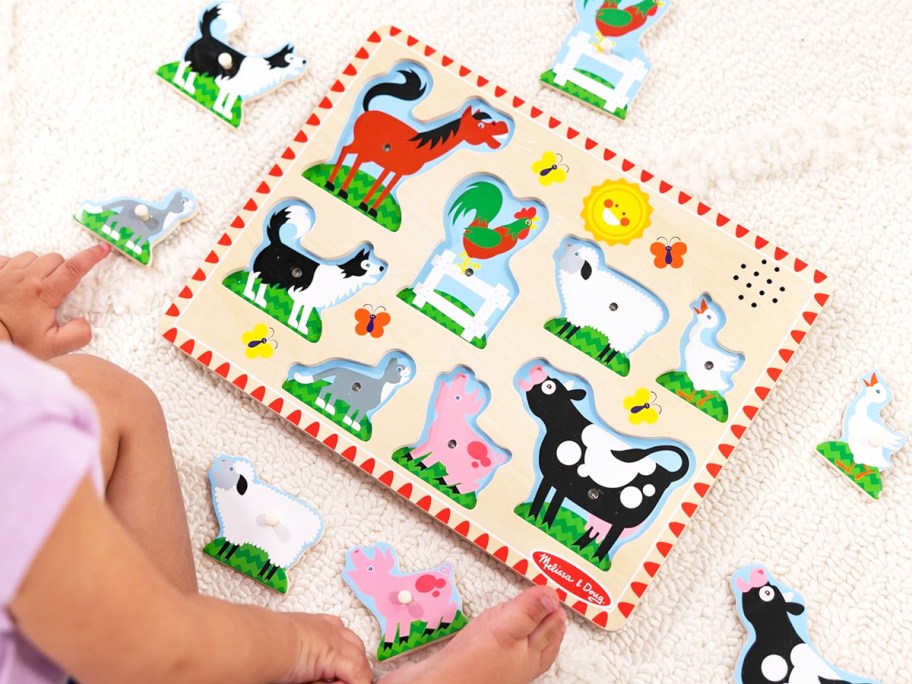 toddler sitting in front of a farm animal wooden puzzle