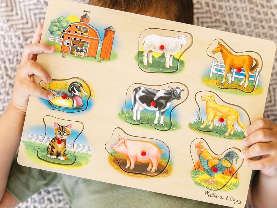 boy holding a wooden farm animals puzzle 