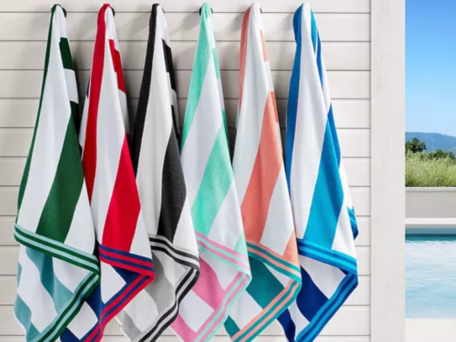 Striped beach towels hanging on hooks on white wooden wall