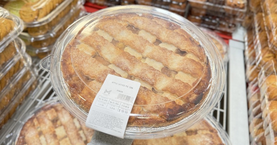 hand holding up a large apple pie from sams club