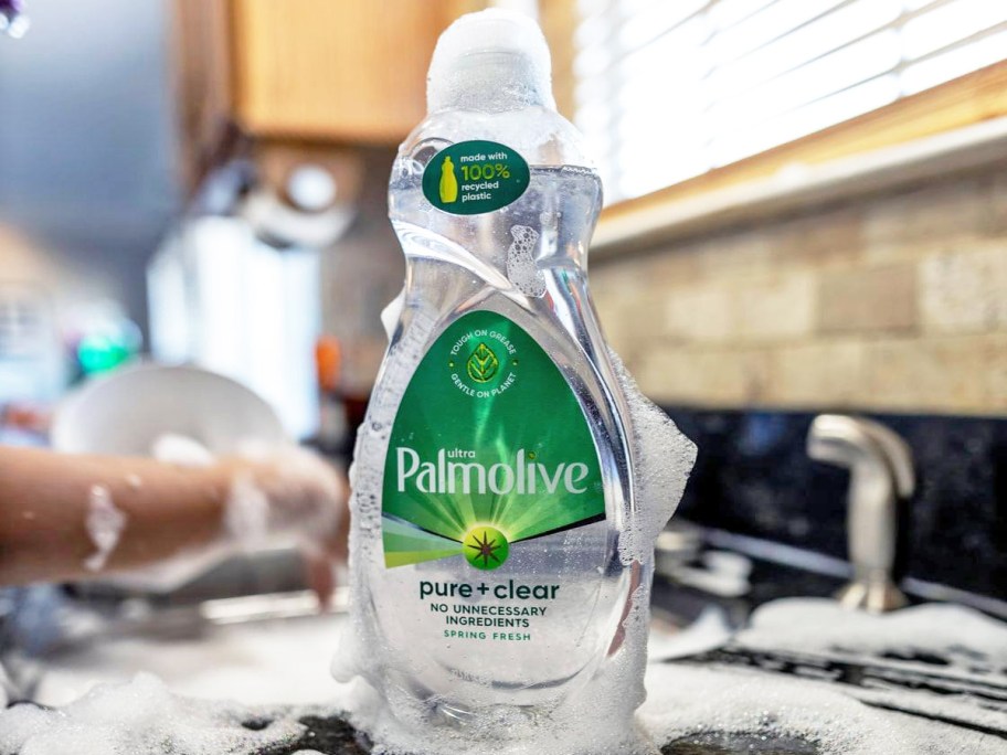 bottle of Palmolive Ultra Pure + Clear Dish Soap covered in suds next to kitchen sink