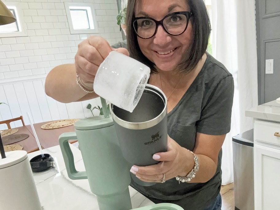 woman holding up ice cylinder and stanley tumbler