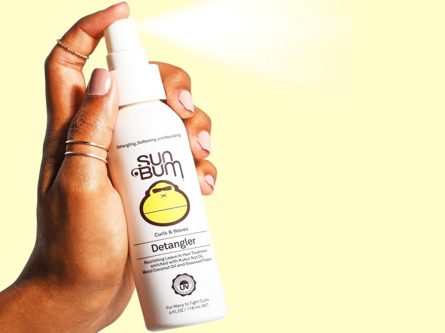 hand spraying a bottle of Sun Bum Detangler