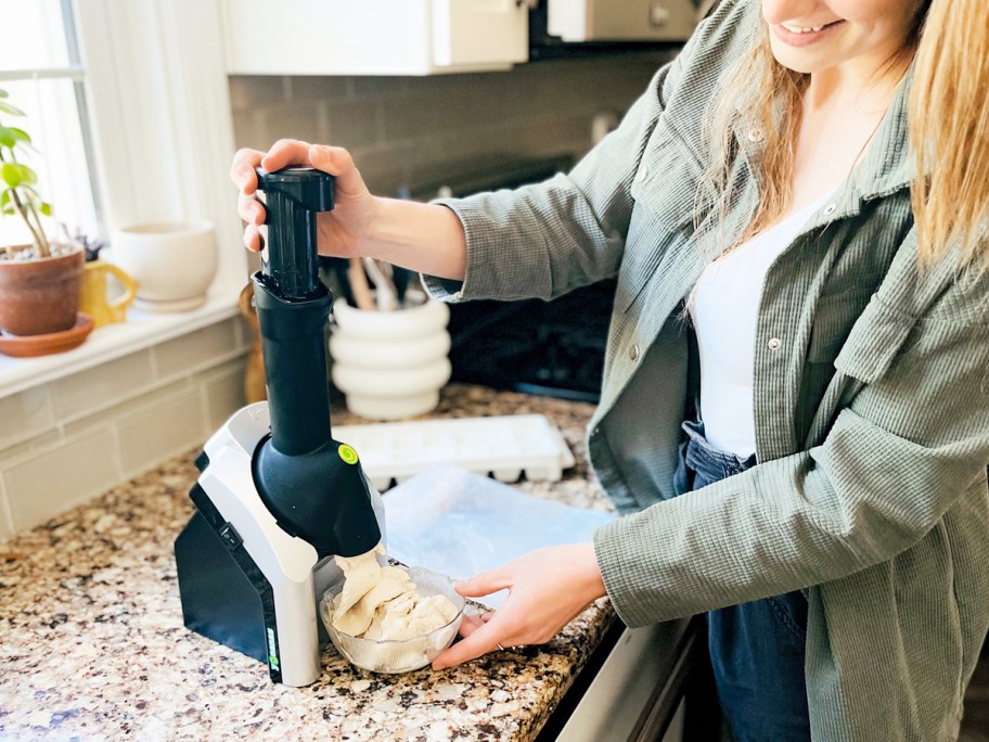 woman pushing down chute on Yonanas frozen treat maker with soft serving onlineing out into a bowl