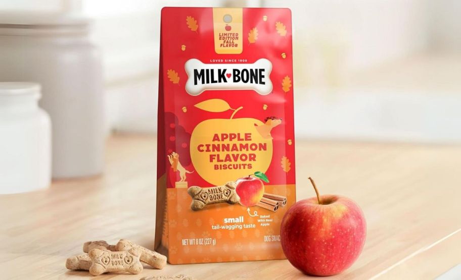 a bag of apple cinnamon milk bone dog biscuits shown with an apple on a kitchen counter