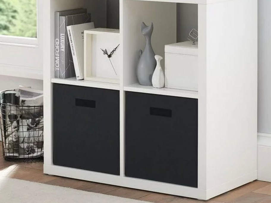 two black storage bins in white book shelf