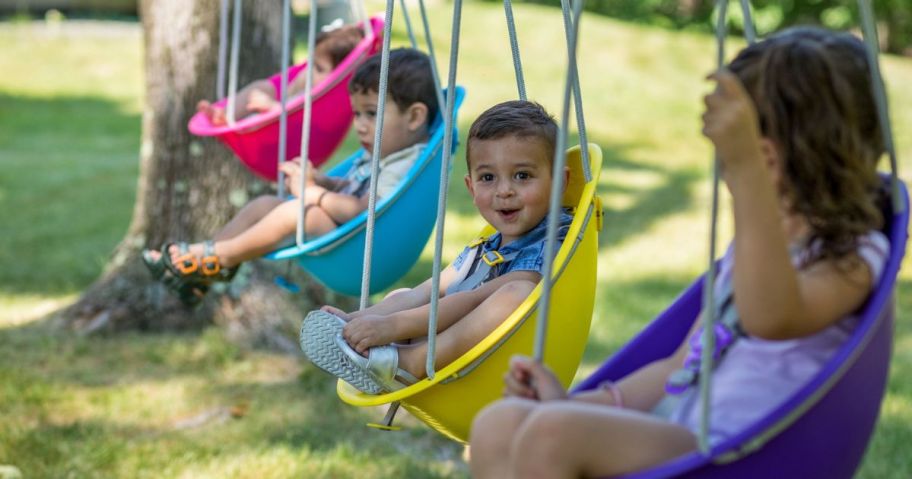 4 Swurfer Coconut Swings in a line on a swingset with children in them