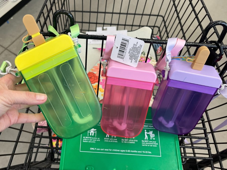 hand holding a large popsicle shaped drink tumbler with more in the background