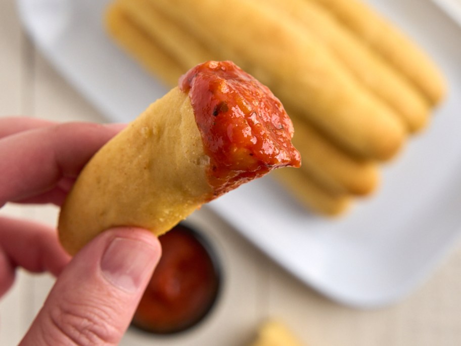 dipping a breadstick in marinara sauce