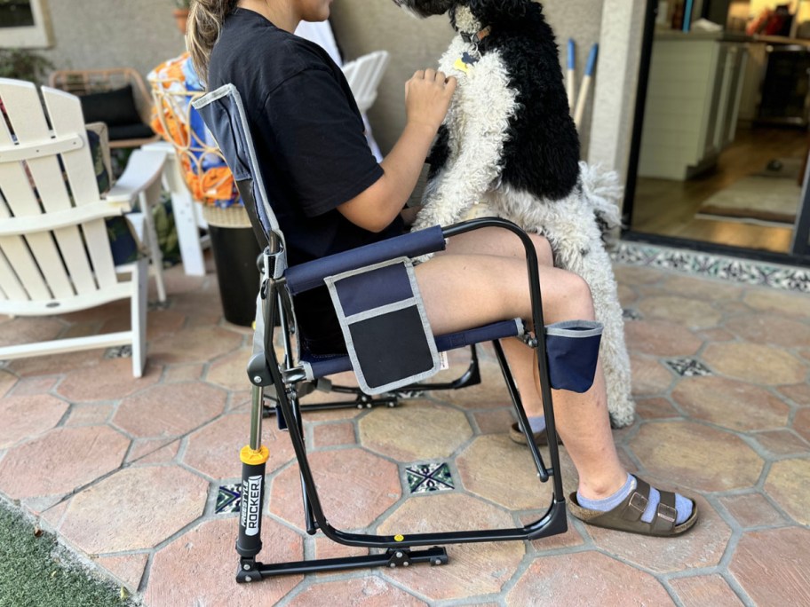 dark blue cgi outdoor rocking chair with girl and dog sitting in it