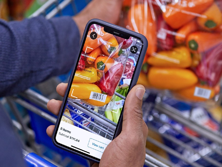 hand holding phone to scan the colorful peppers at sams club