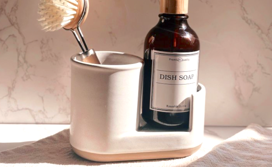 a stoneware sink caddy with a brush and handsoap in it