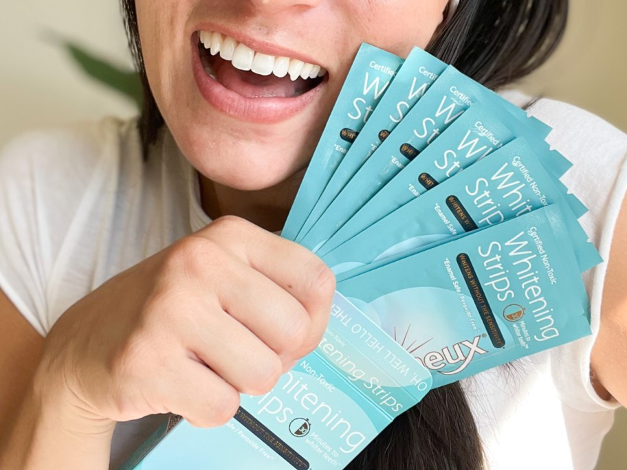 woman holding whitening strips next to face